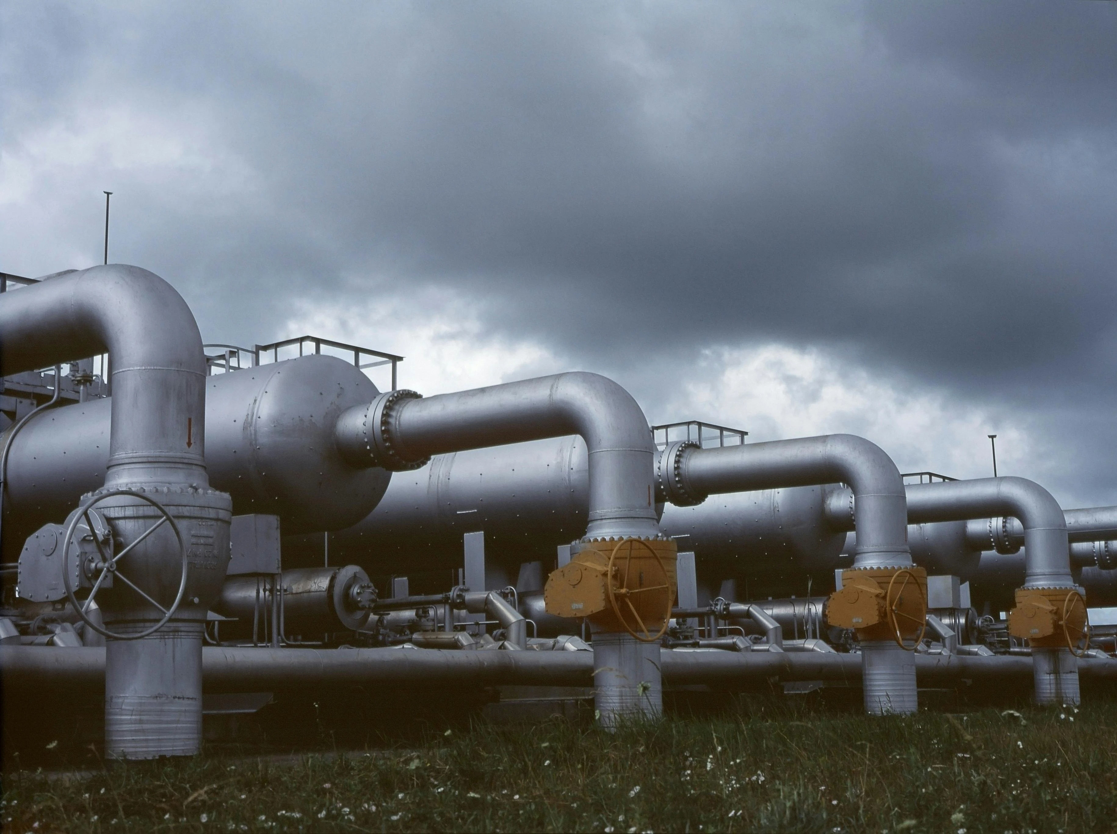 a bunch of pipes are lined up in a field with a cloudy sky in the background